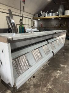 Long stainless-steel extraction canopy run, side view, in our Wednesbury workshop